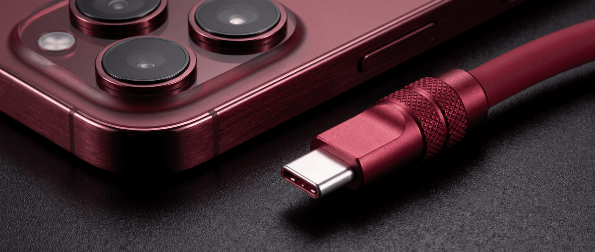 Close-up of a deep cherry red smartphone and a matching USB-C cable connector side by side on a dark textured background.